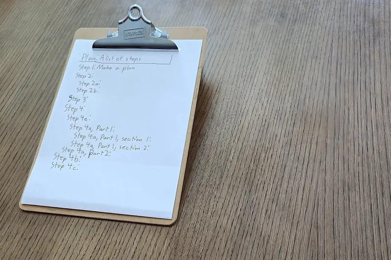 A clipboard holding a sheet with a short handwritten numbered list, lying on a wooden table